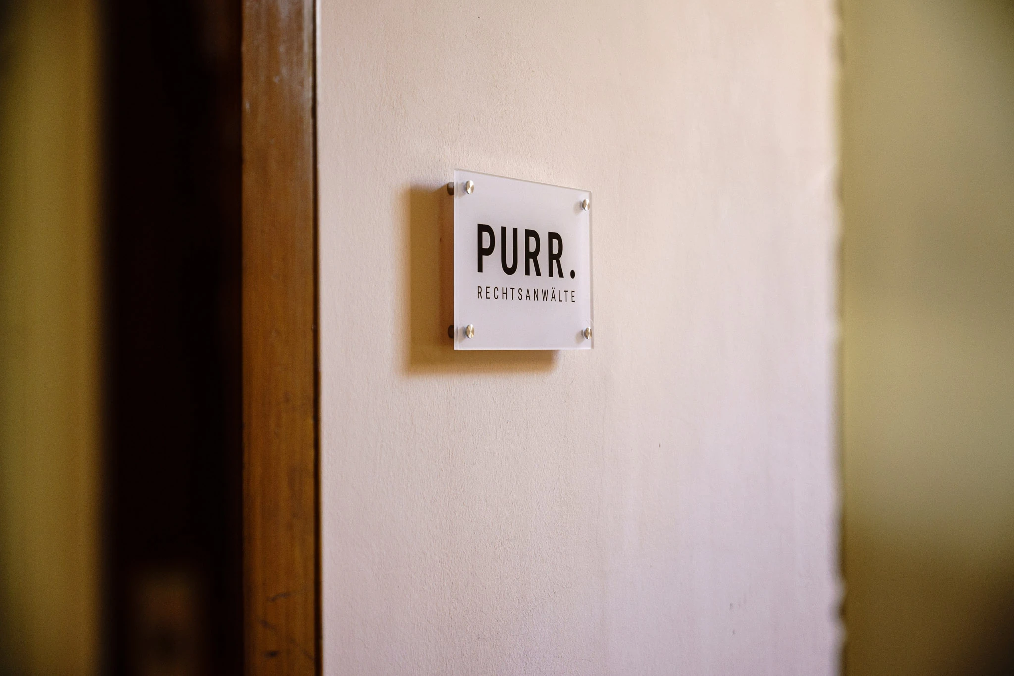 Türschild mit Aufschrift „PURR Rechtsanwälte“ an der Wand im Eingangsbereich der Kanzlei